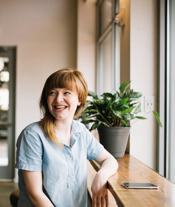 Person smiling while siting at a table with their smartphone lying on the table.